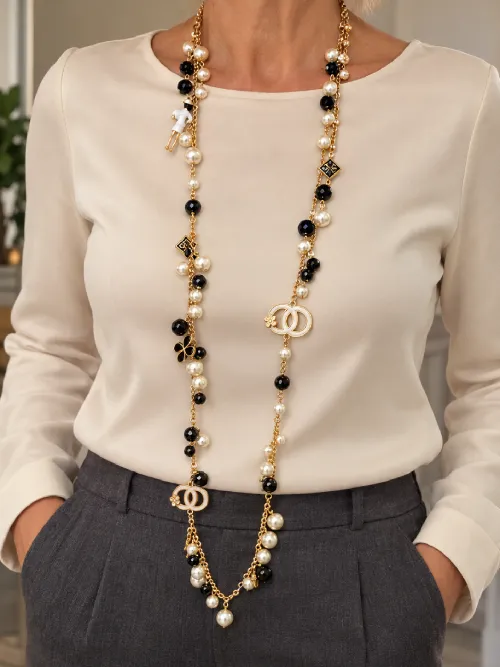 Collana lunga con elementi dorati, neri e perle chiare